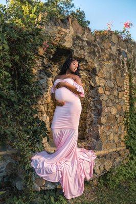 Expectant mother cradles her bump as she enjoys the soft light of the sun on her face