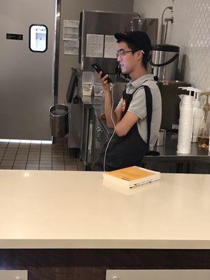 Another worker on his phone instead of making the drinks for people.