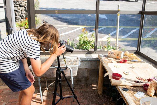 A student is photographing seeds from the school's farm that will be for sale to the community.