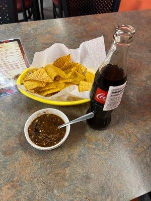 Chips with salsa on the table and a mexica Coca-Cola.