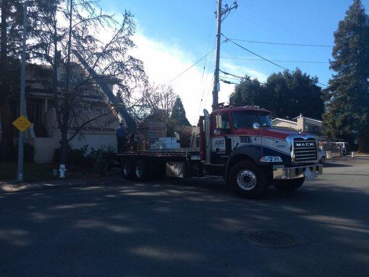 truck with conveyor used to load roofing shingles directly to top of next door 3 story house