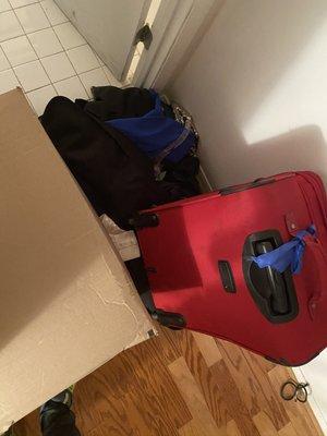 suit bag thrown on the ground with box and suitcase left on top