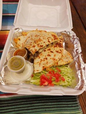 Steak and cheese quesadilla with lettuce, chopped tomato and sour cream.