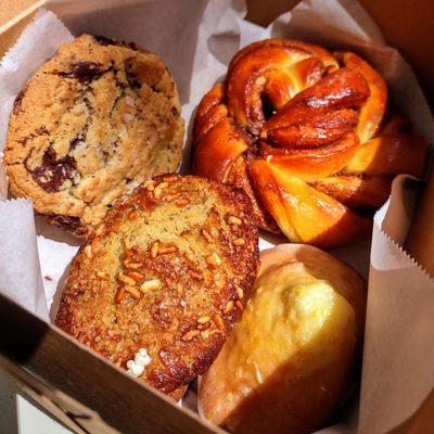 Clockwise from top left: chocolate chip cookie, cinnamon roll, lemon madeleine, miso banana loaf. Pesto focaccia not pictured.