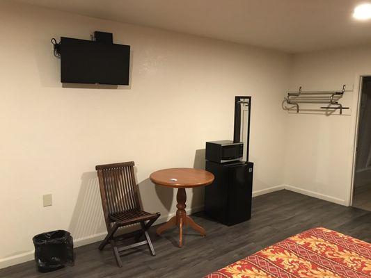 Flat screen TV, wooden seat and table, microwave and mini fridge