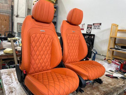 2021 Mercedes Benz G-64 AMG seats wrapped in leather.  The orange color is contrasted with black stitching for design.