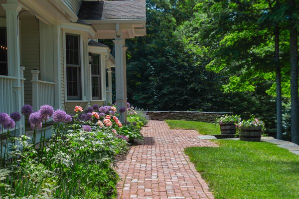 Perennials and bulbs lining a brick walkway and pergola.