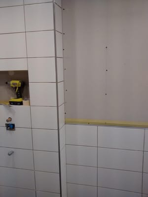 Tile is being installed flush with the drywall, creating clean linear lines and a smooth looking transition to the paint...