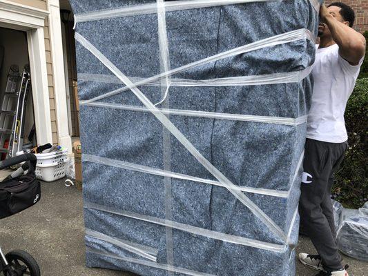 Bronx, NY Moving Associate Geehantee is seen wrapping & protecting a massive bureau before loading it onto a rental truck  J Sutton and Co