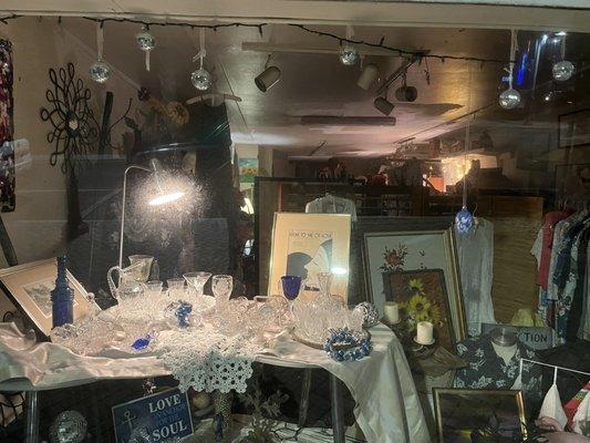 Their right window showing Hanukah antiques with some antique art and shirt rack in the background.