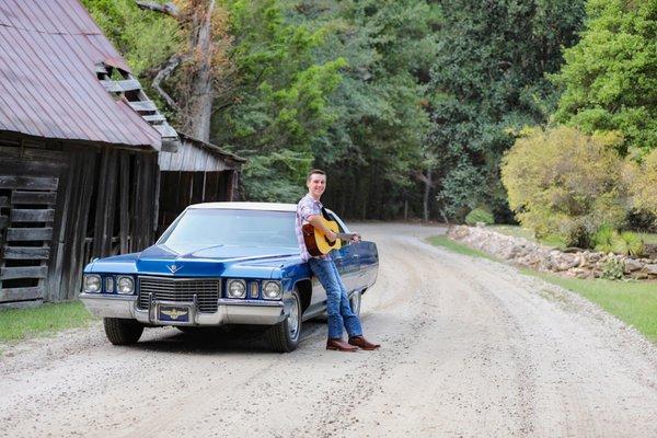 Portrait of a high school senior boy leaning against his Grandpa's vintage car on a dirt road.