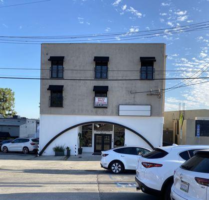 Large tan and white business building with entrance located near the parking lot behind the building.