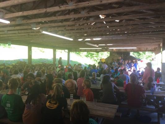 Outdoor mess hall full of noisy, happy campers.