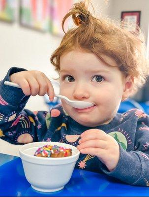 Scoops and spoons young girl eating an ice cream sundae