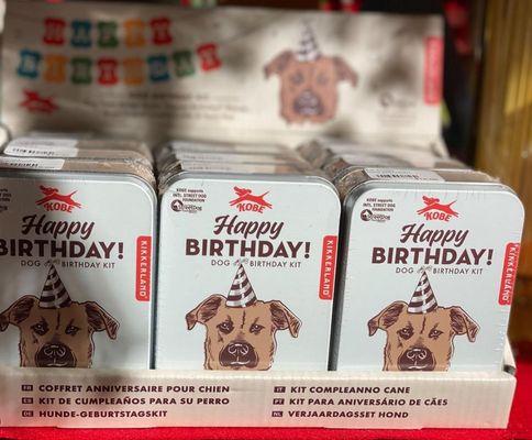 Happy Birthday Dog Kit with a dog treat recipe book, bone-shaped cookie cutter, "Happy Birthday !" banner, and party hat. ⁠