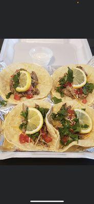 Jerk chicken taco with shredded cheese, cilantro, tomatoes, onions, sour cream, and freshly cut lemons.